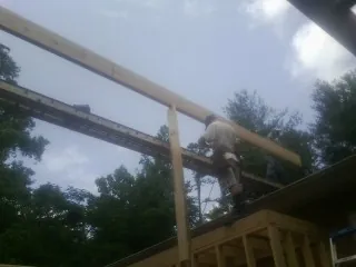 Carpenter setting a ridge beam over a new addition frame — Ice Dam Removal by Roofing Brothers in Crete