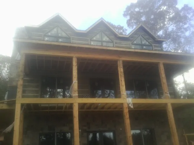 Dormers and porch framing on a large log home under construction — Roof Coating work by our crew in Crete