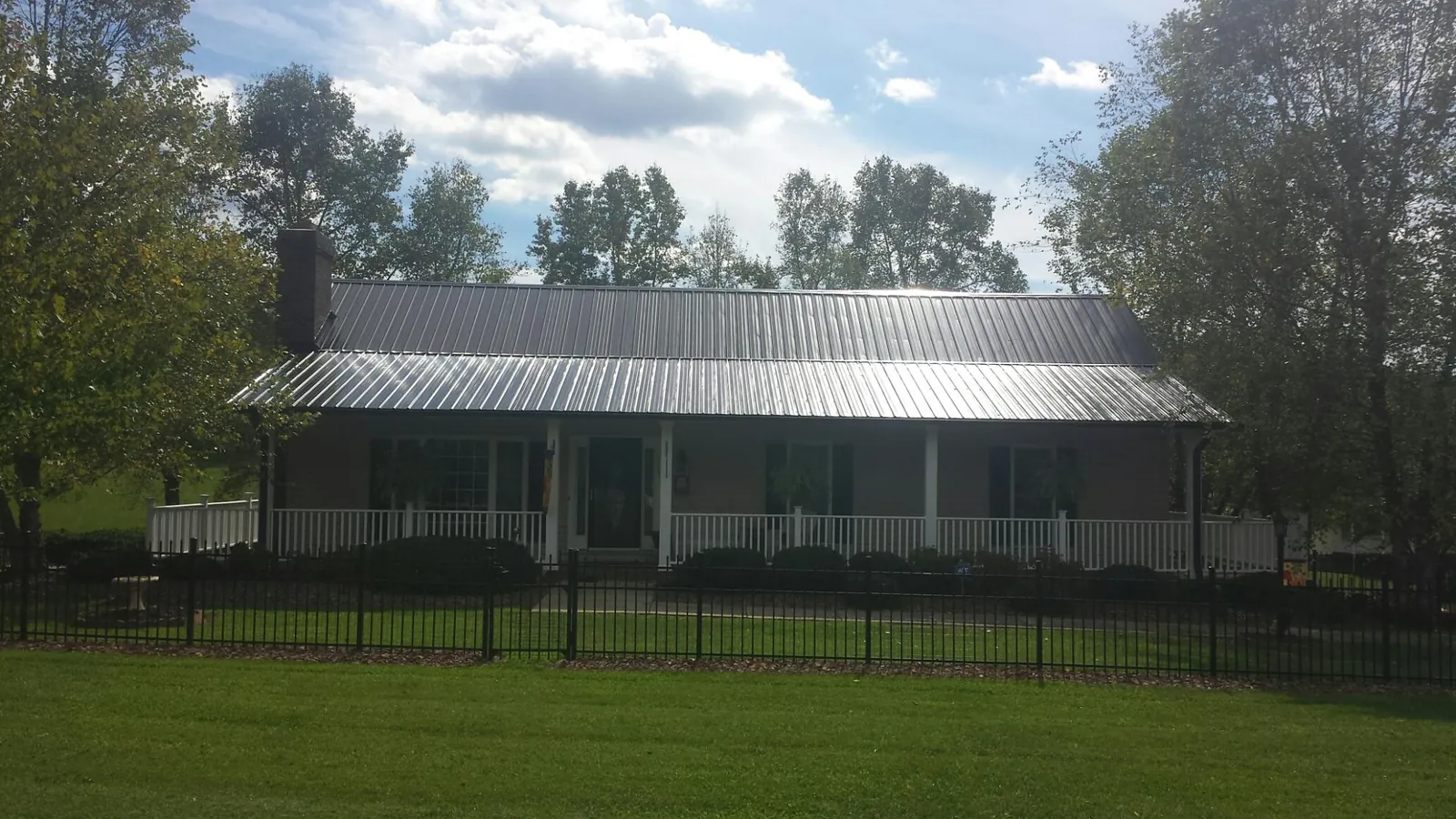 Gray metal roof on a brick ranch with a full width front porch — Gutter Guard Installation work by our crew in Crete