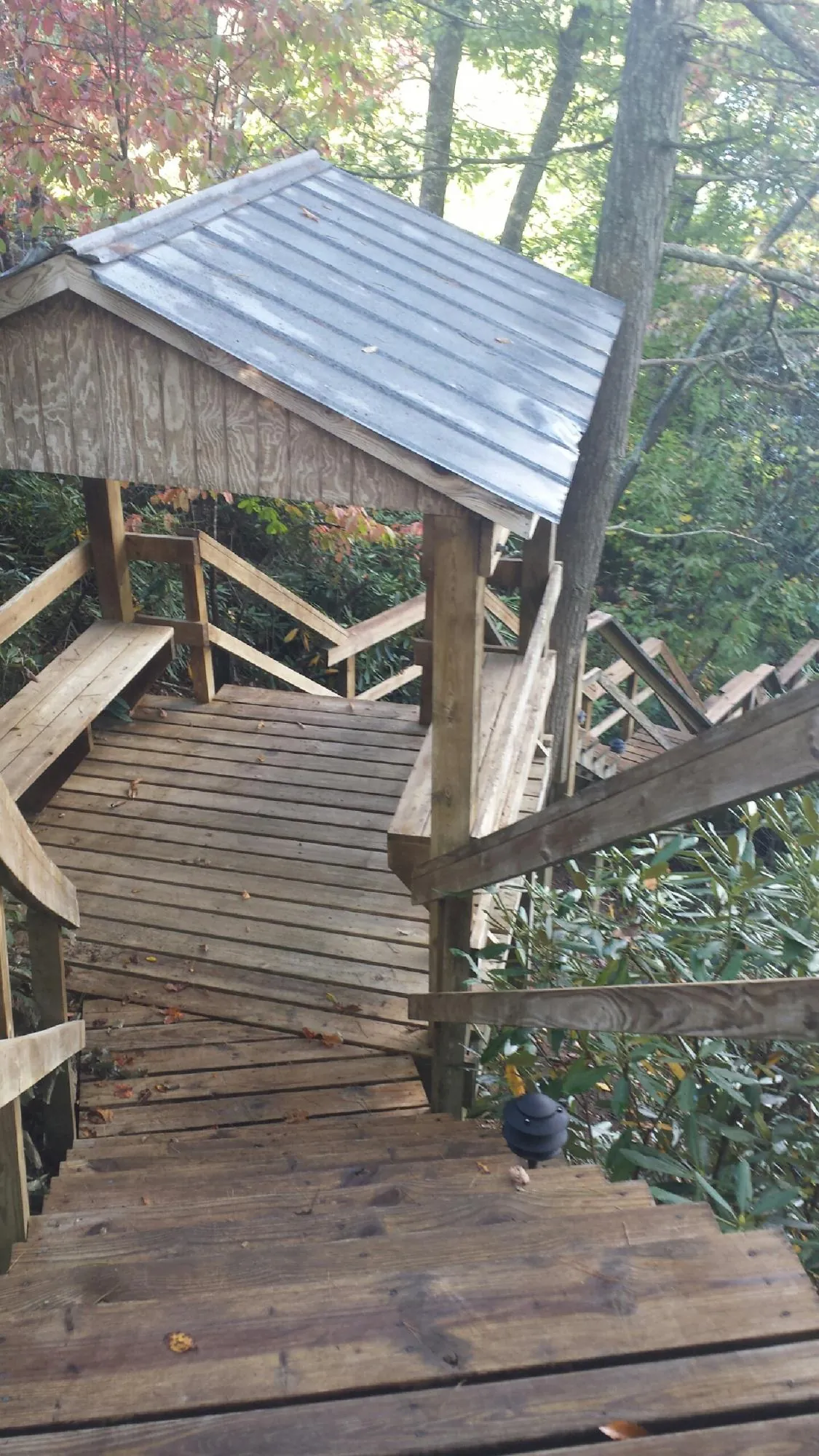 Metal roofed shelter over wooden steps on a wooded walkway — Skylight Repair & Installation work by our crew in Crete