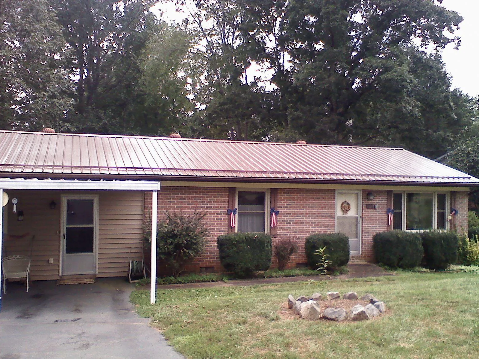 Bronze metal roof and carport on a brick ranch home — Roof Repair work by our crew in Crete