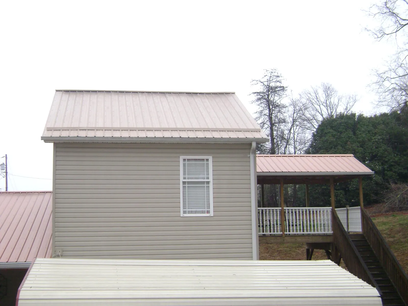 Tan metal roofs on a two story addition and attached porch, from a Roof Replacement job in Crete