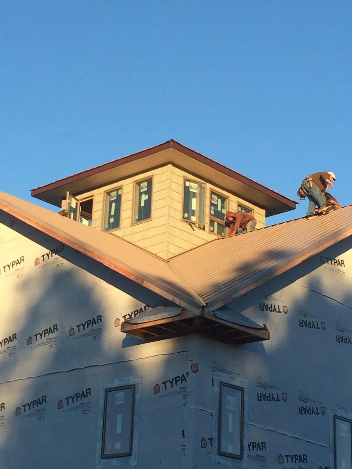 Roofers working around a rooftop cupola on a new metal roof at sunset — Roof Waterproofing in Crete by Roofing Brothers